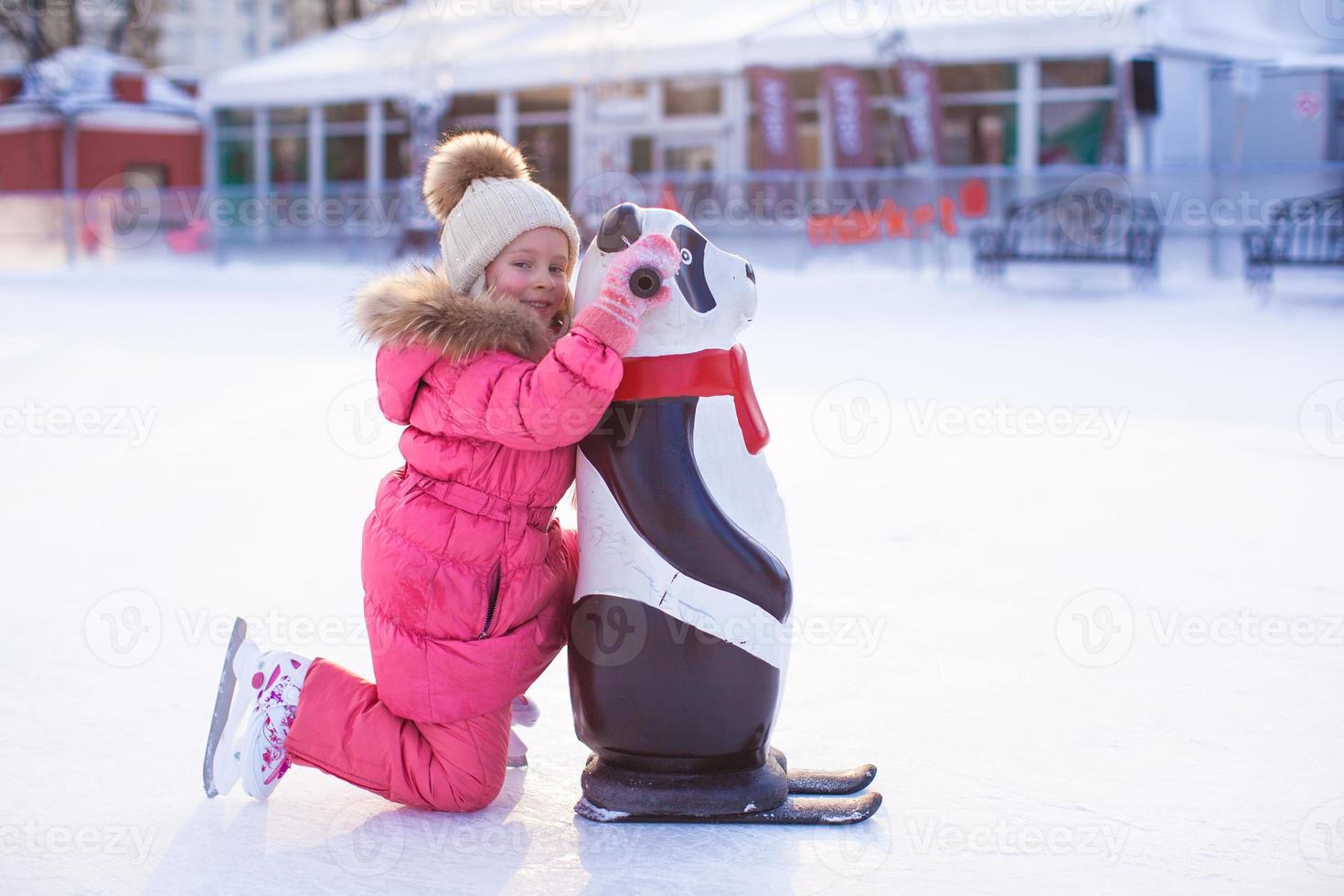 Little happy girl skating on the ice-rink photo