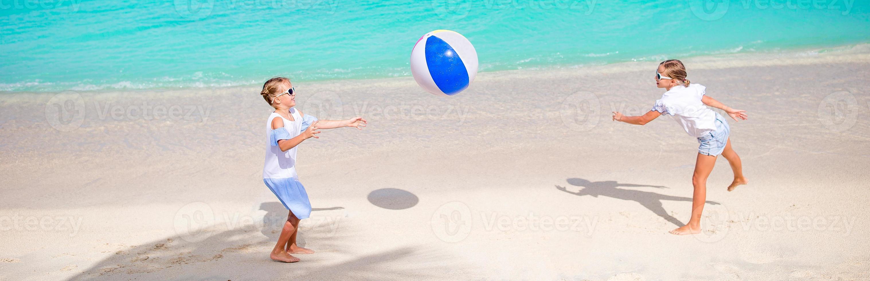 Little adorable girls playing on beach with air ball photo