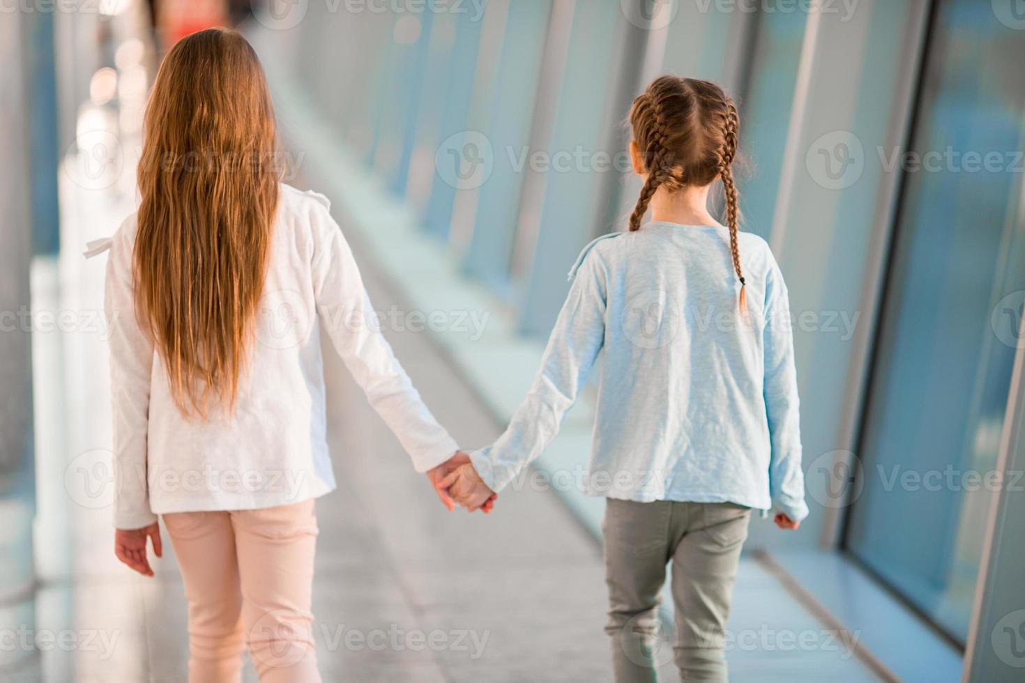 Little girls in airport near big window inside while wait for boarding photo