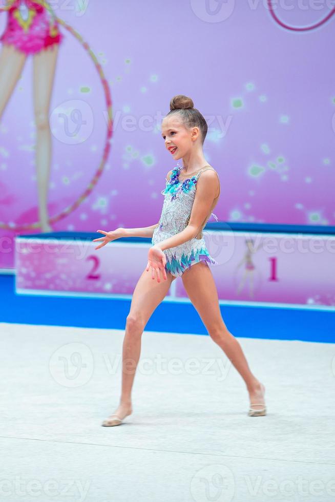 Beautiful little gymnast girl on the carpet on the competition photo