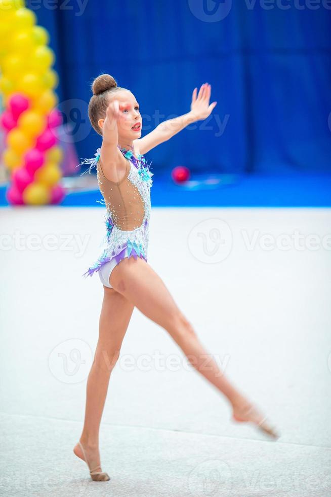 Beautiful little gymnast girl on the carpet on the competition photo