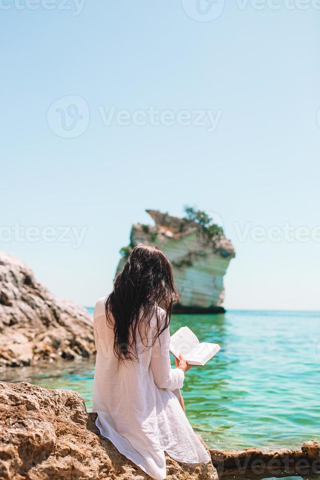 mujer joven leyendo en la playa blanca tropical foto