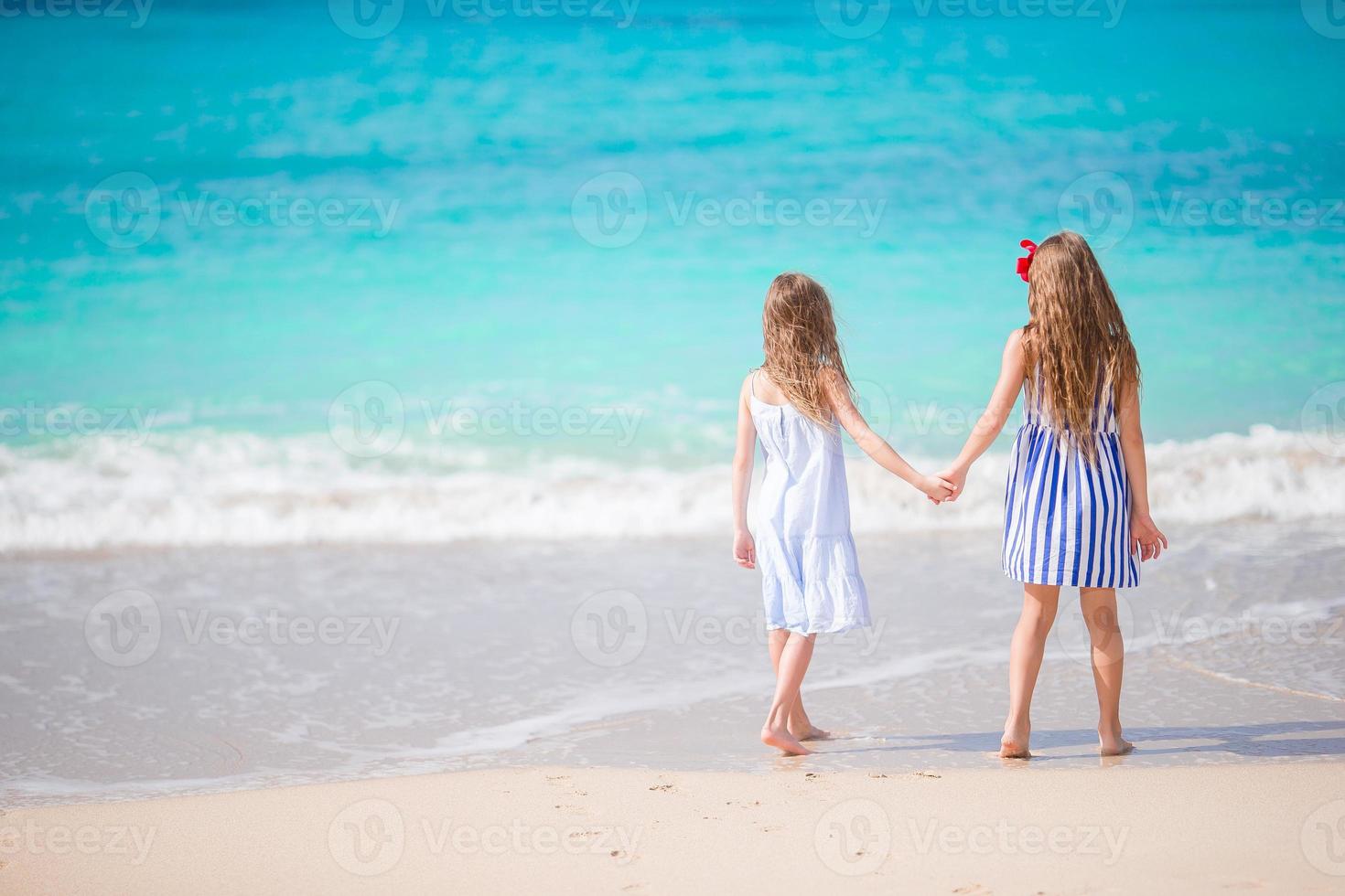 Adorable little girls walking on the beach photo