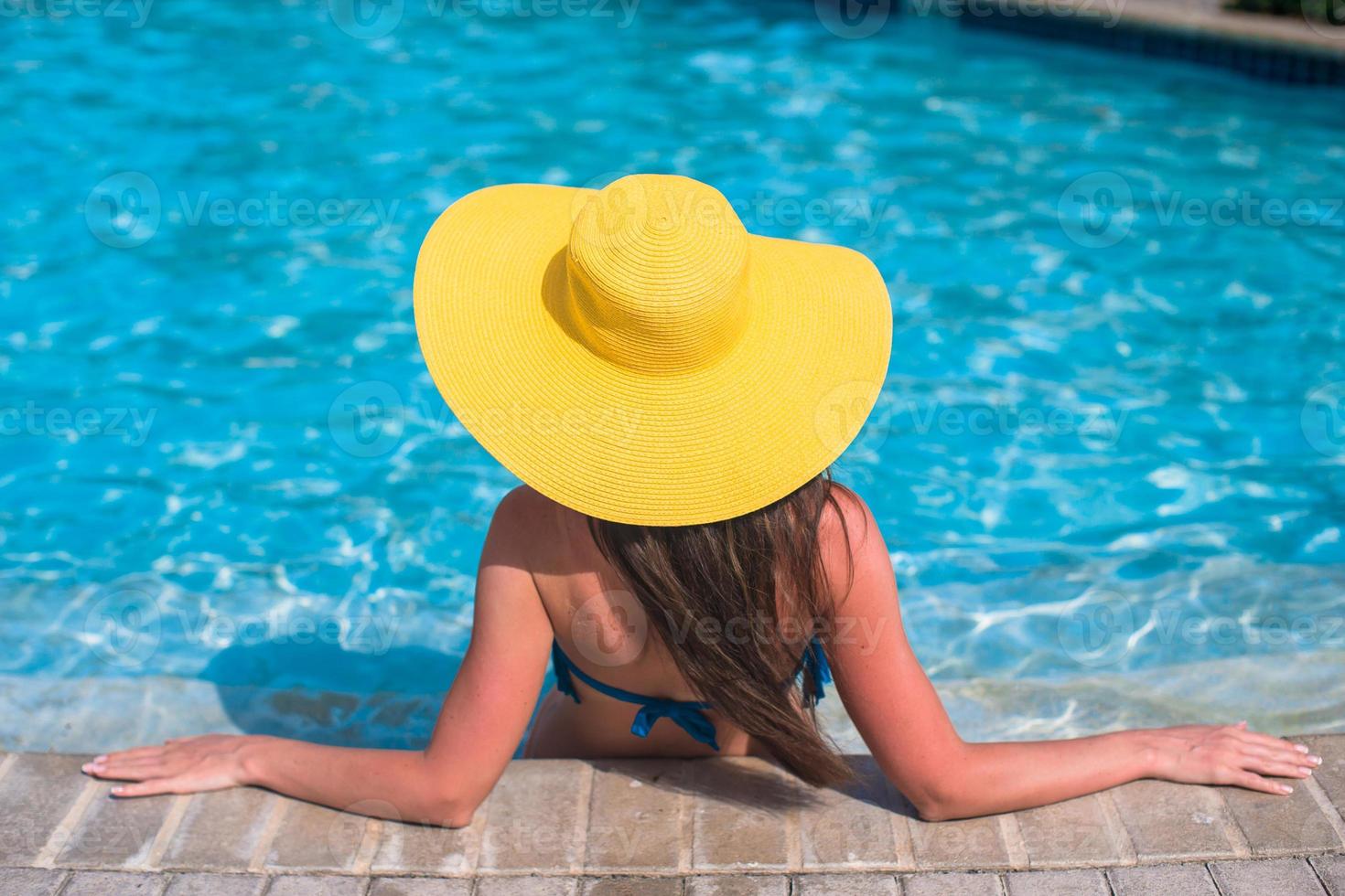 Young beautiful woman enjoying vacation in the pool photo