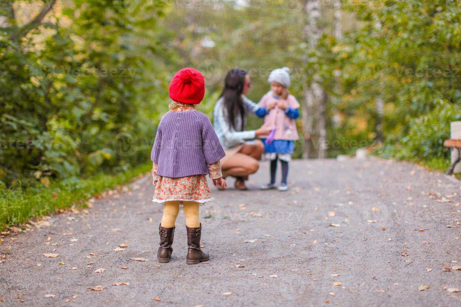 joven madre con sus adorables hijas felices divirtiéndose al aire libre en el parque de otoño foto