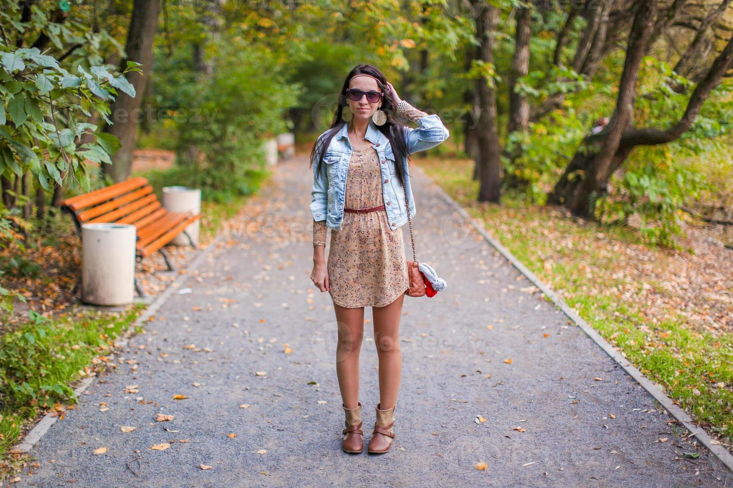 Fashion young beautiful girl walks in the park on a sunny autumn day photo