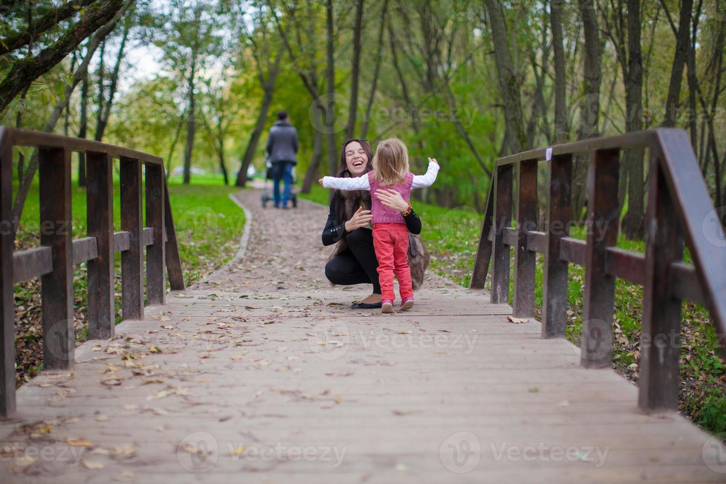 joven madre caminando con su pequeña hija en el parque otoño foto