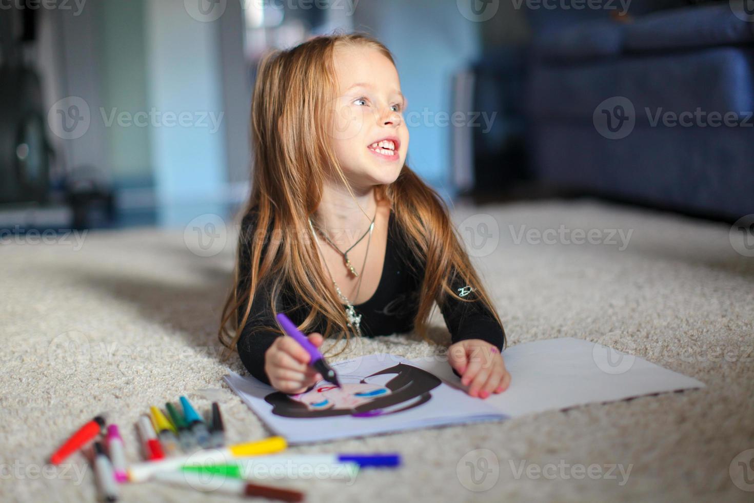 Portrait of a sweet charming young girl who draws with his coloring at home photo