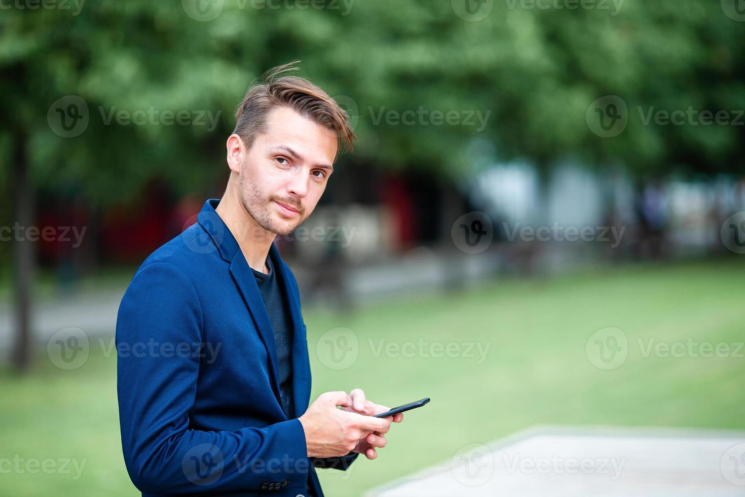 Man is reading text message on mobile phone while walking in the park photo