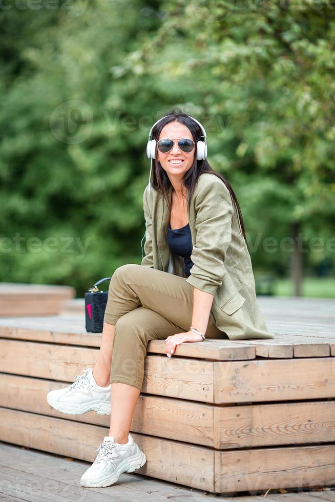 Cute woman is reading text message on mobile phone while sitting in the park. photo