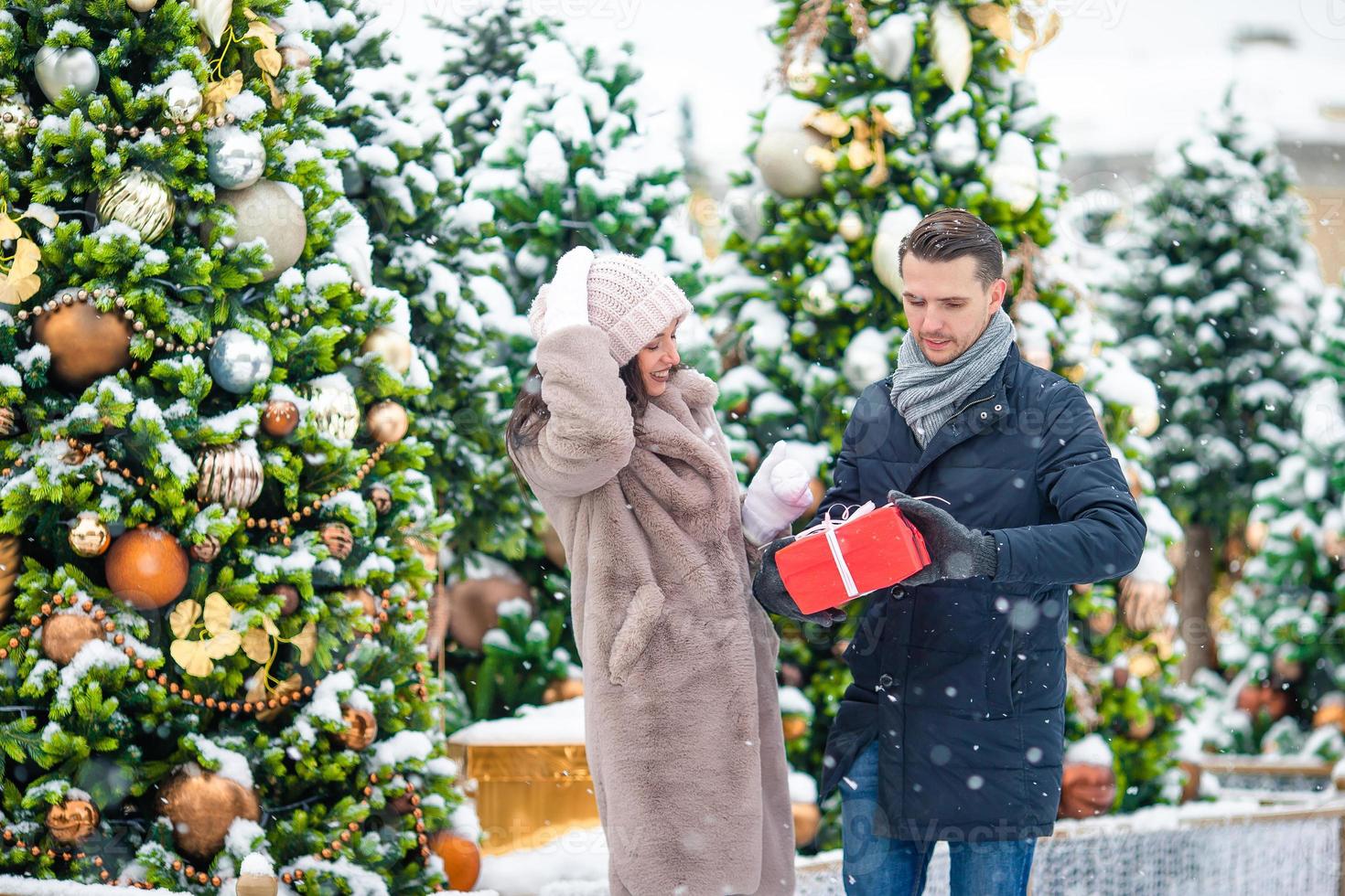 joven hermosa pareja alegre celebrando la navidad en la calle de la ciudad  y dándose regalos el uno al otro. 17708692 Foto de stock en Vecteezy