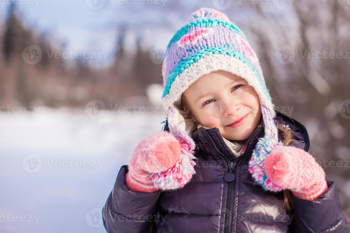 Portrait of little adorable girl in winter hat at snowy forest photo
