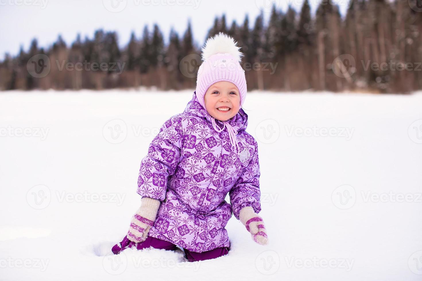 niña feliz divirtiéndose en la nieve en el día soleado de invierno foto