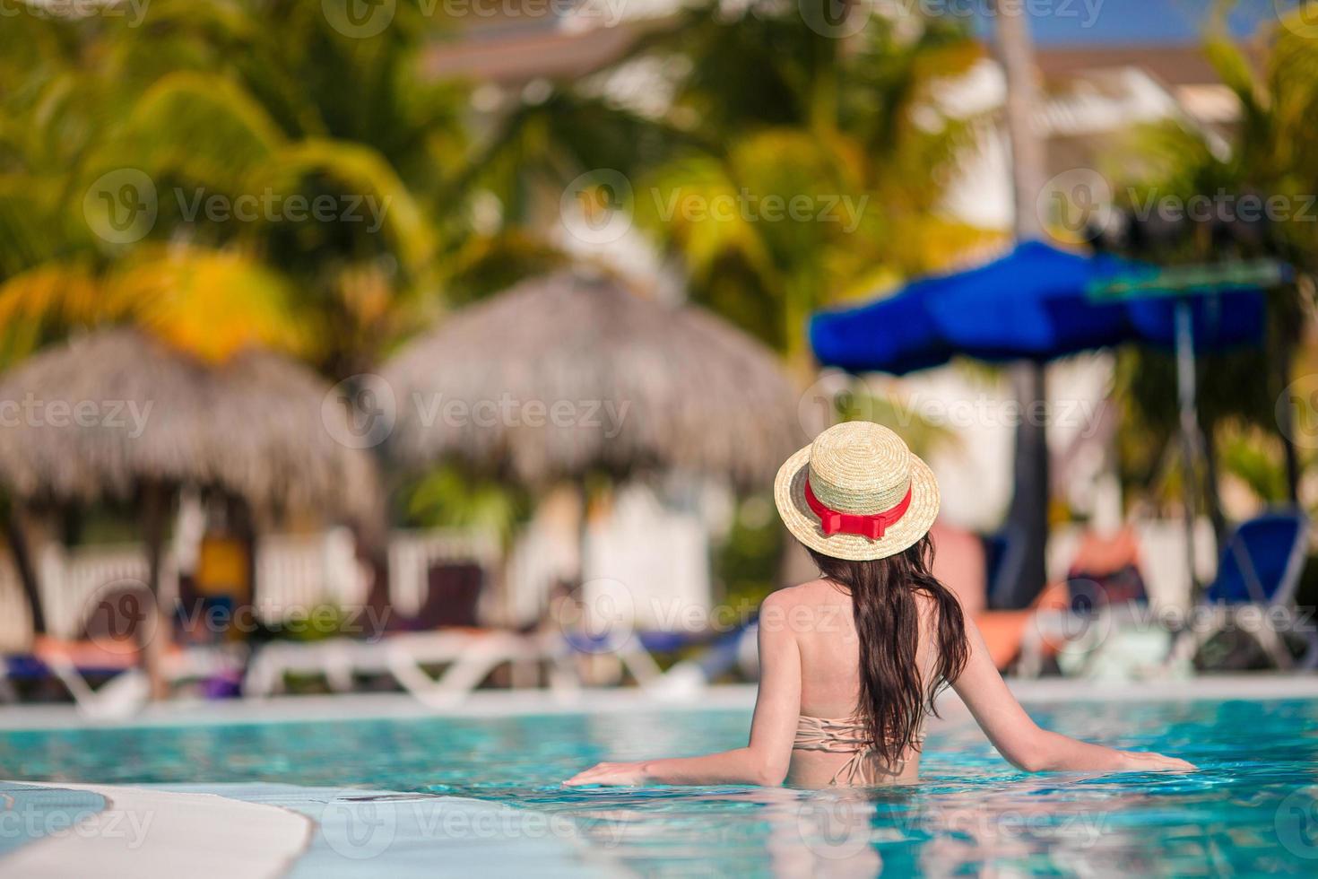 Beautiful young woman relaxing on the edge of infiniti pool photo
