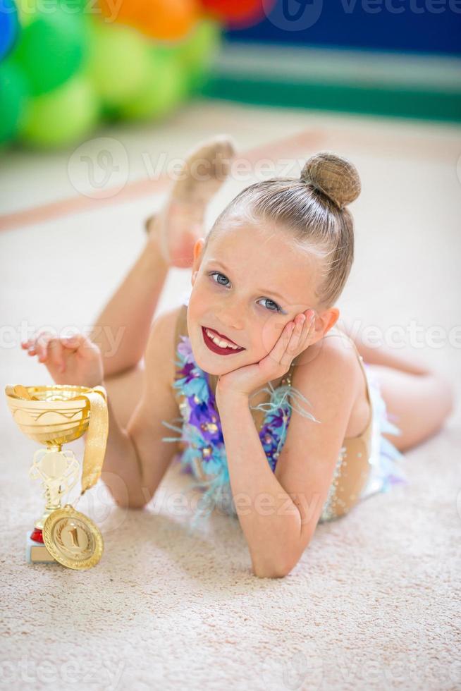 hermosa pequeña gimnasta entrenando en la alfombra y lista para las competiciones foto