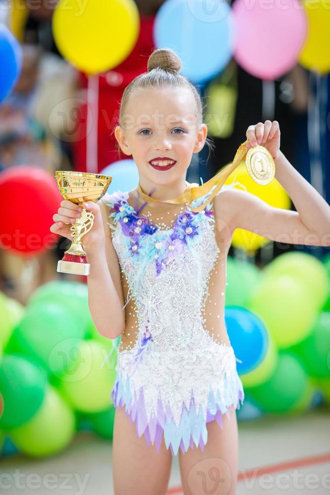 hermosa pequeña gimnasta entrenando en la alfombra y lista para las competiciones foto