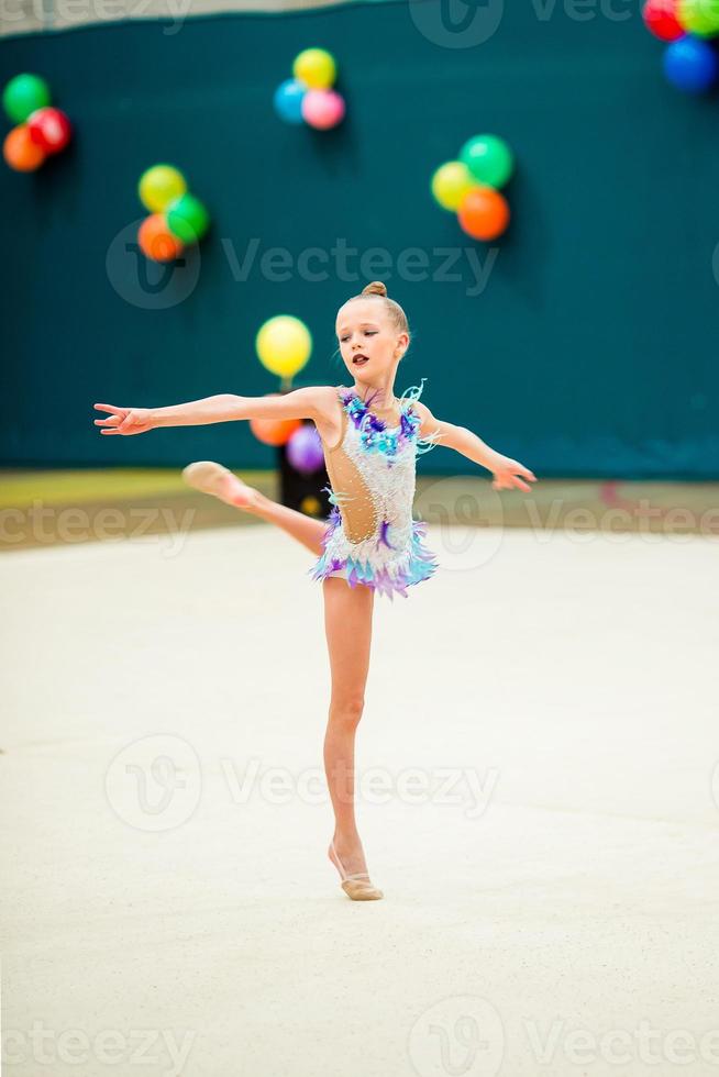 Beautiful little active gymnast girl with her performance on the carpet photo