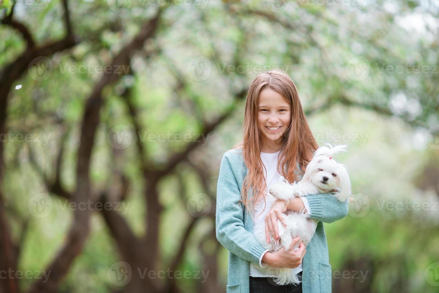 Little smiling girl playing and hugging puppy in the park photo