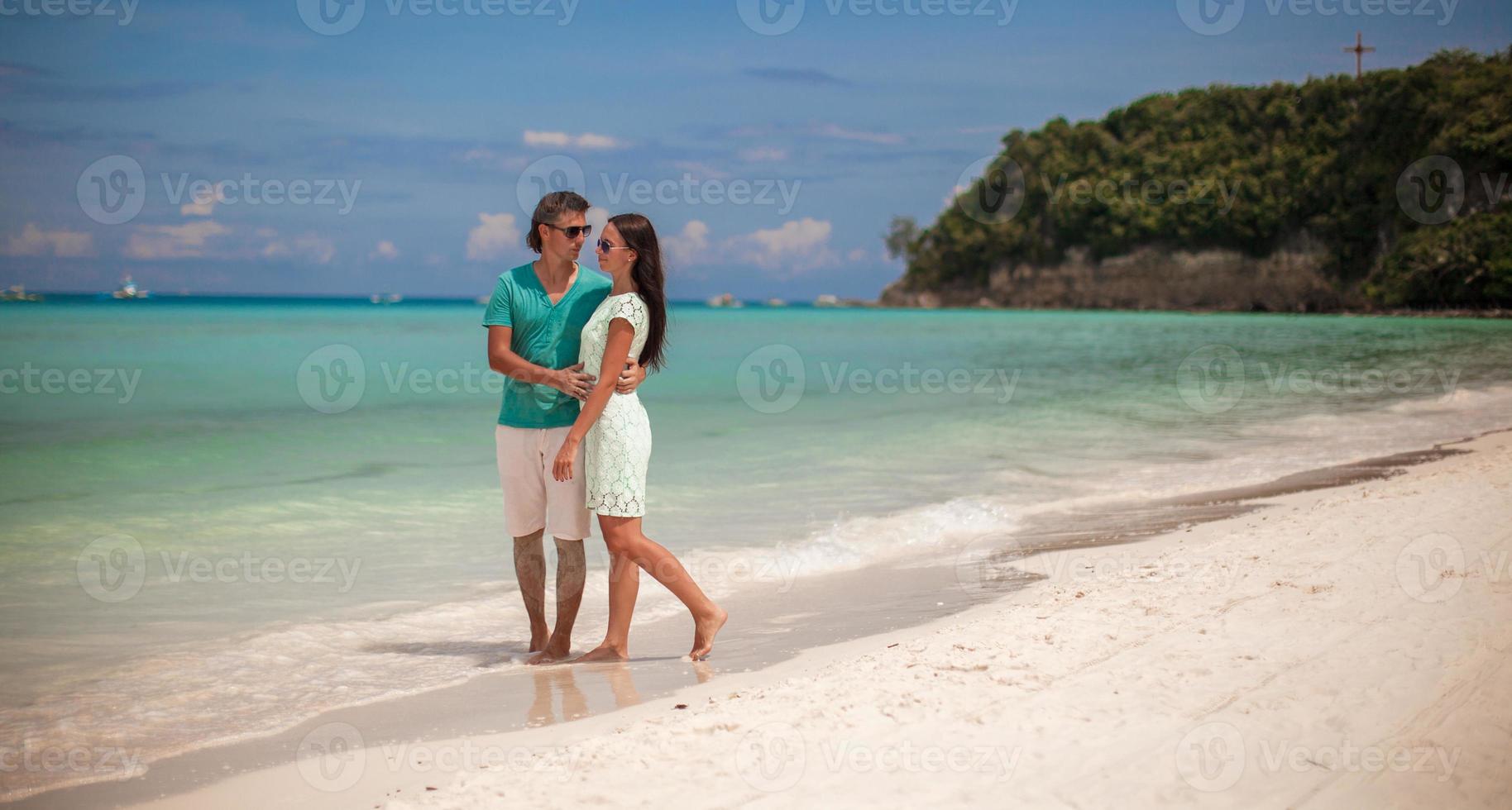 Young couple enjoying each other on sandy white beach photo