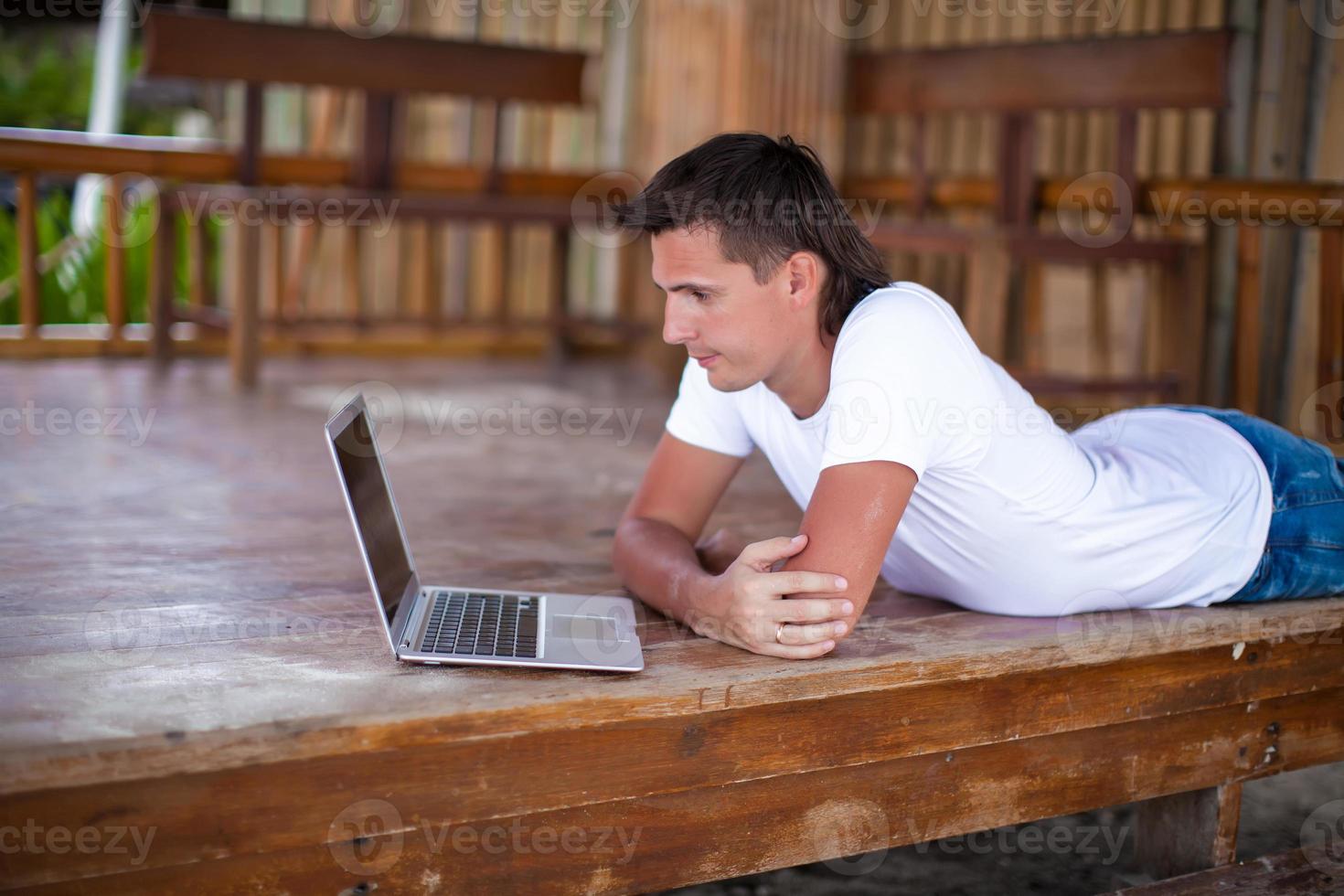 Closeup young man using tablet computer on exotic resort photo