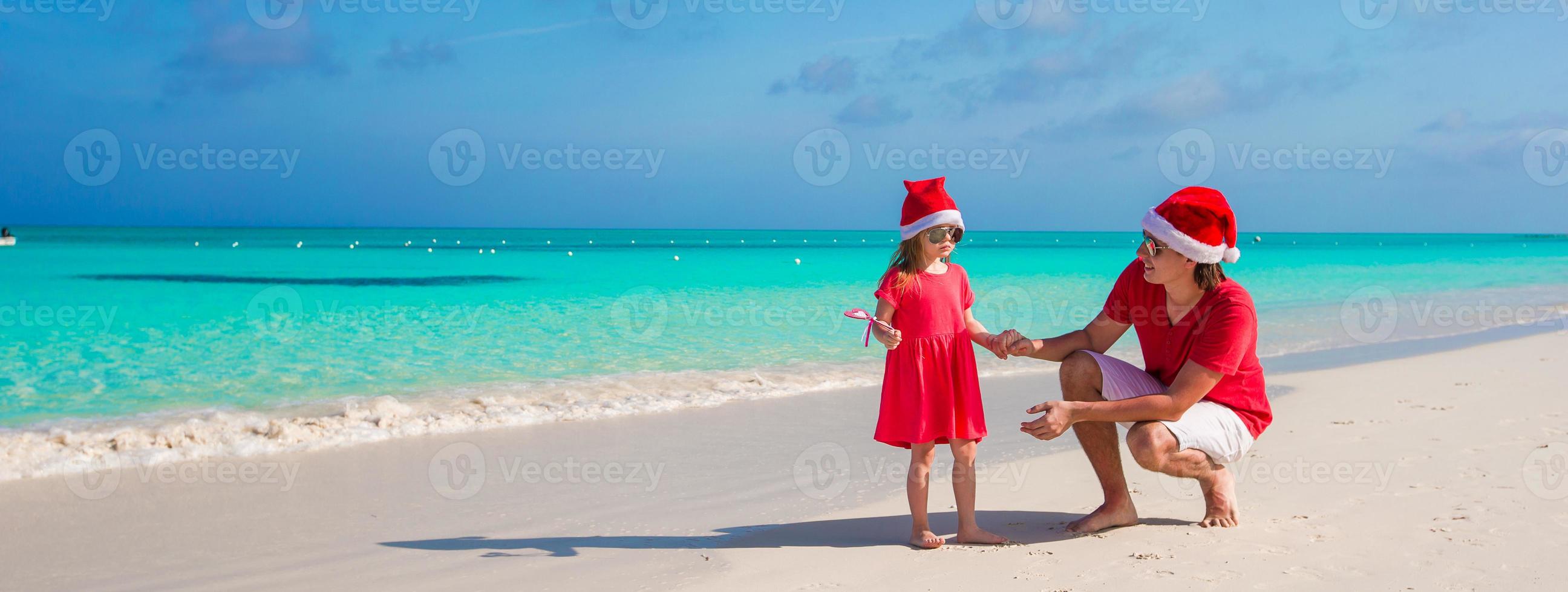 Niña y papá feliz en santa hat en playa exótica foto