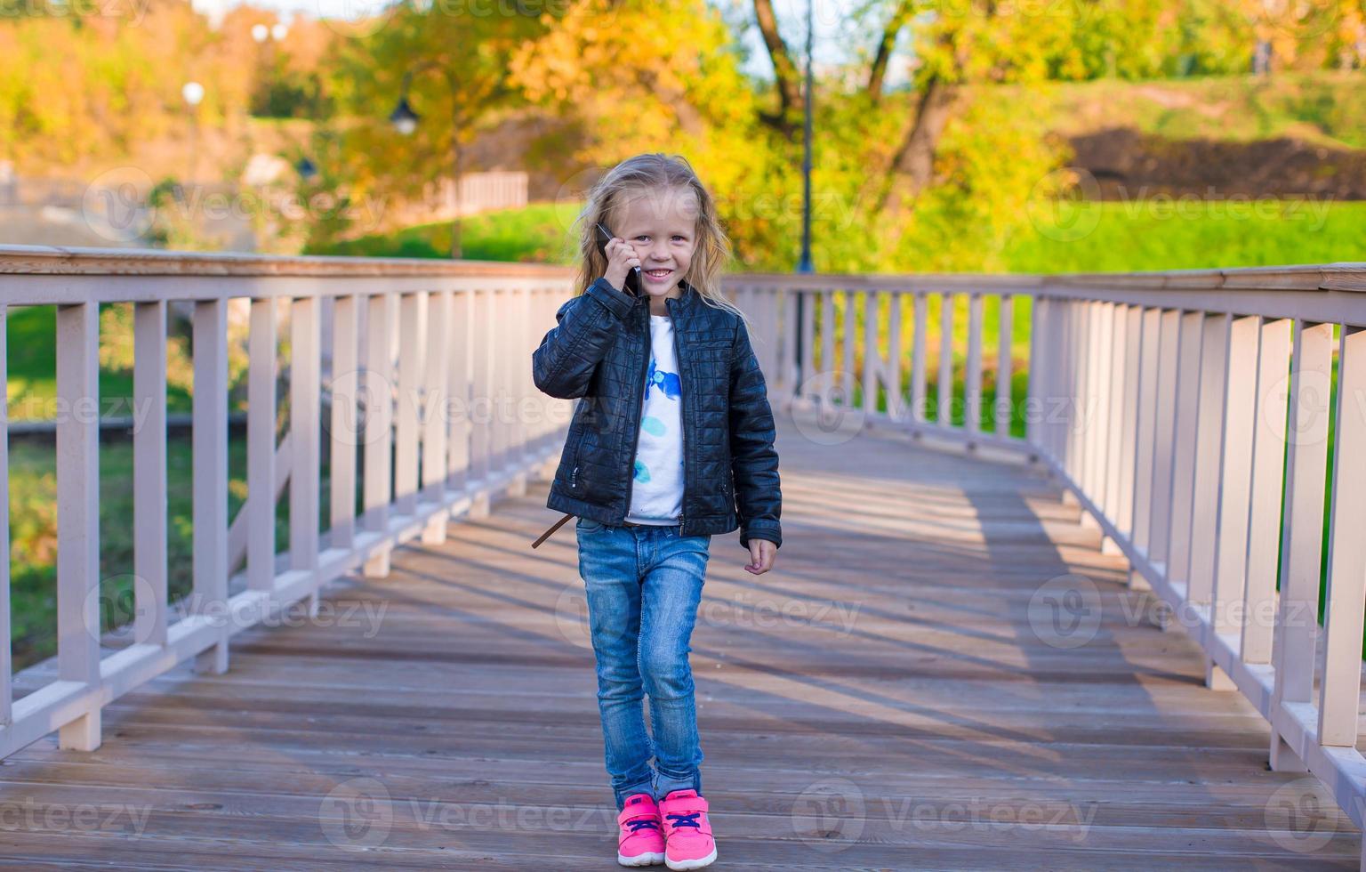 Happy little girl at warm autumn day outdoors photo