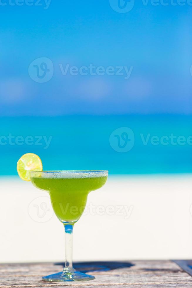 Green tasty cocktail on tropical white beach photo