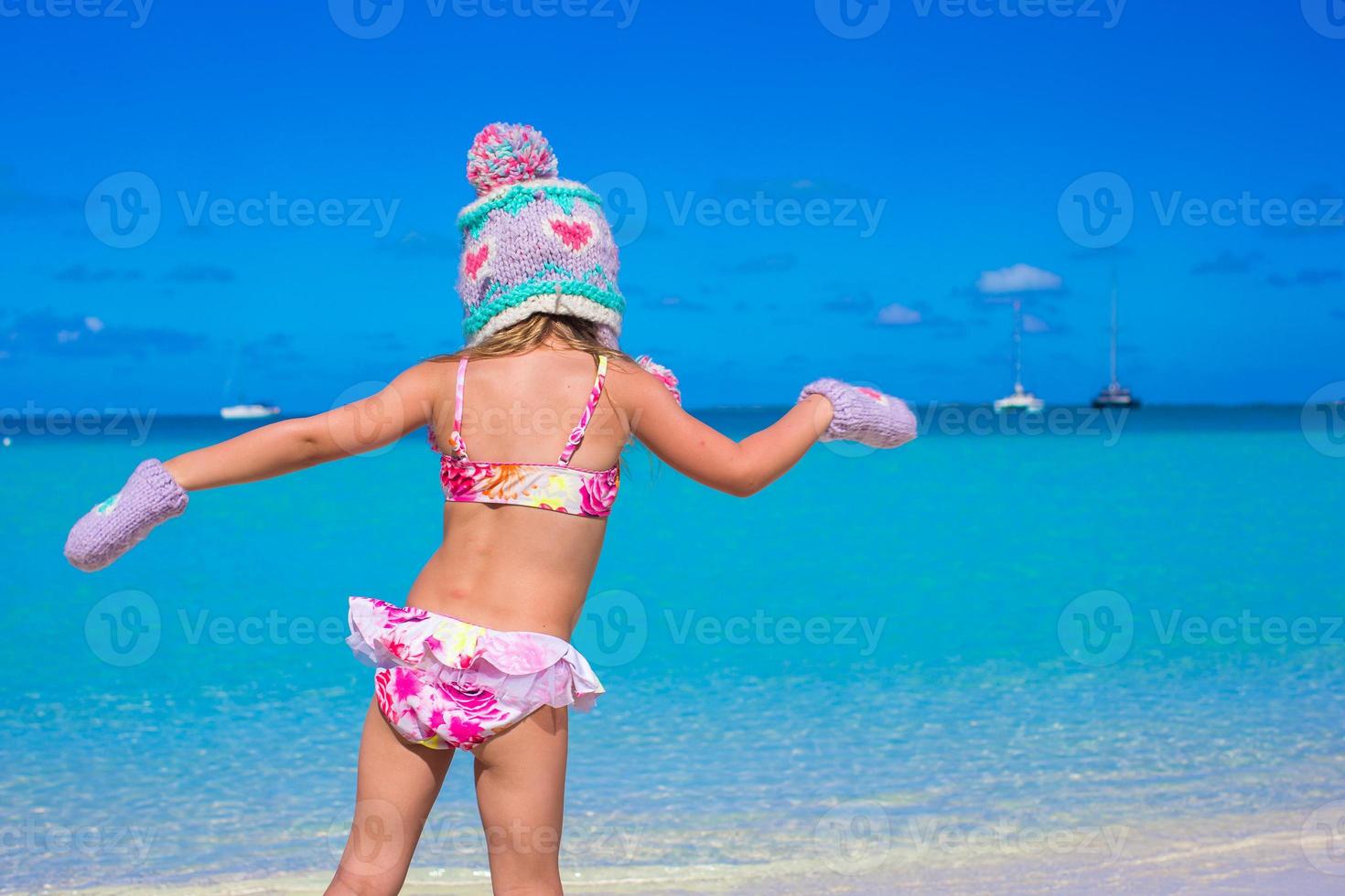 Little girl in warm hat and mittens on beach photo