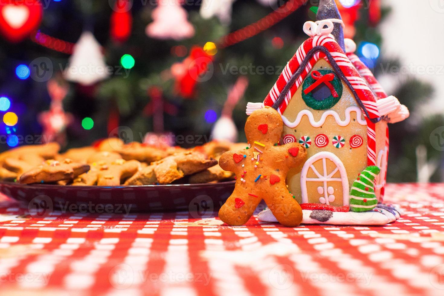 Cute gingerbread man in front of his candy ginger house background the Christmas tree lights photo