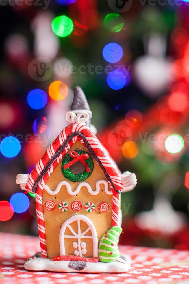 casa de hadas de pan de jengibre decorada con dulces coloridos sobre un fondo de árbol de navidad brillante con guirnalda foto