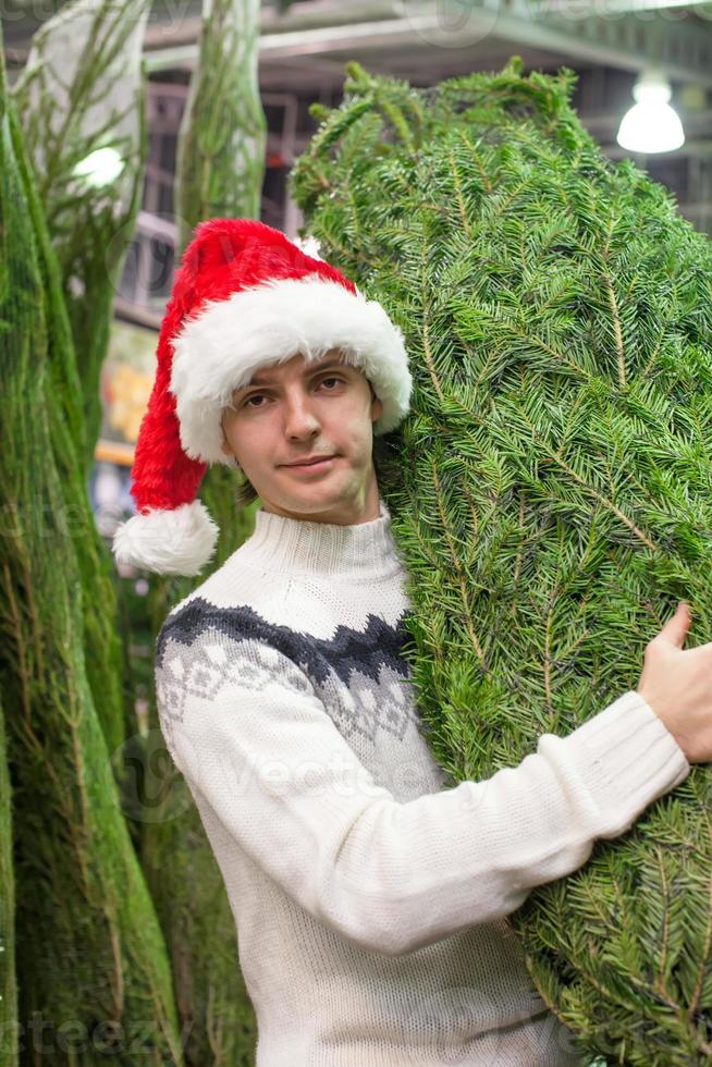 Young man buying a Christmas tree in the store photo