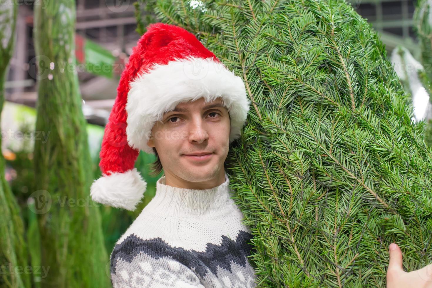 Young man choose a Christmas tree in the store photo