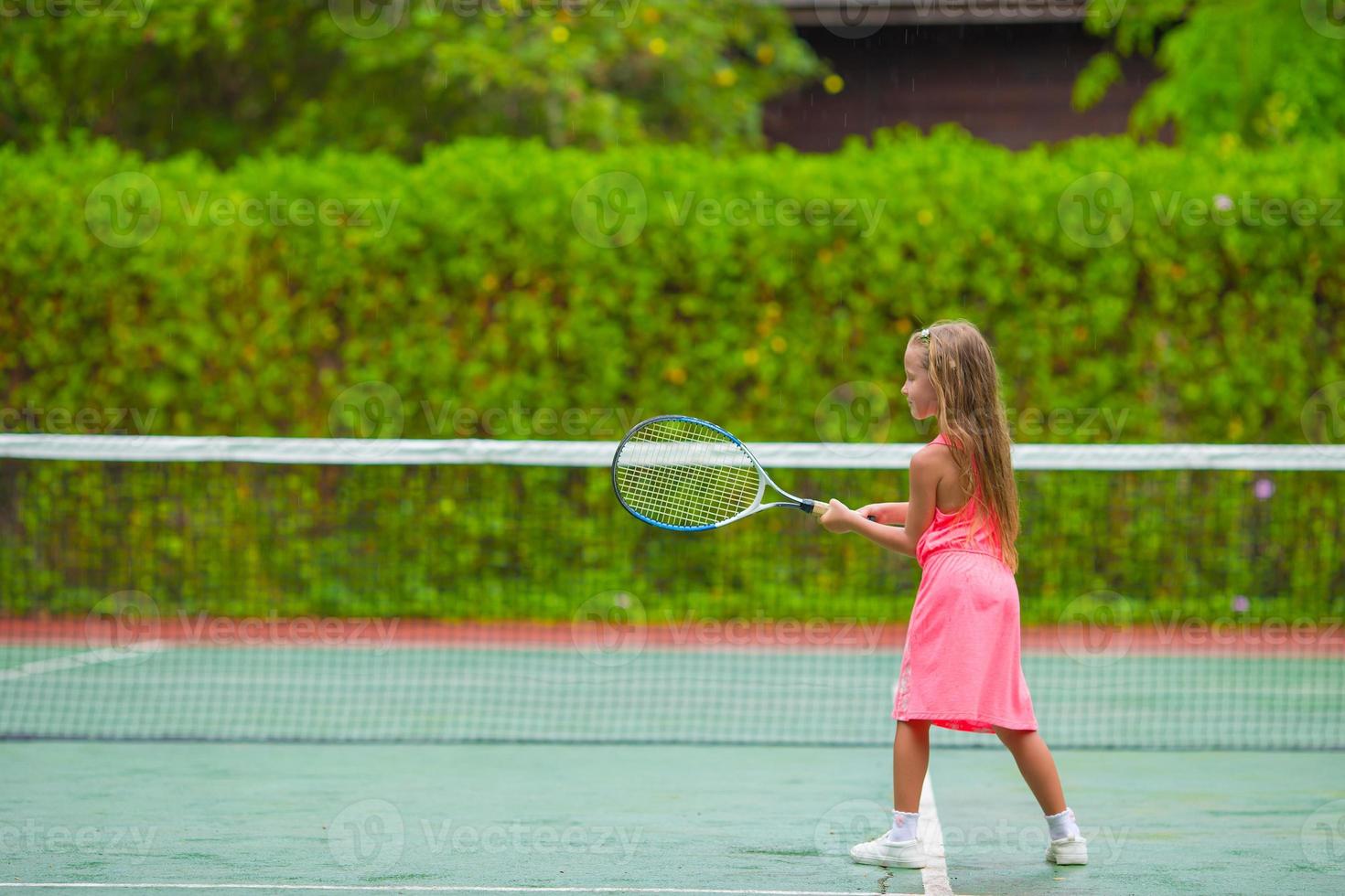 niña jugando tenis en la cancha foto