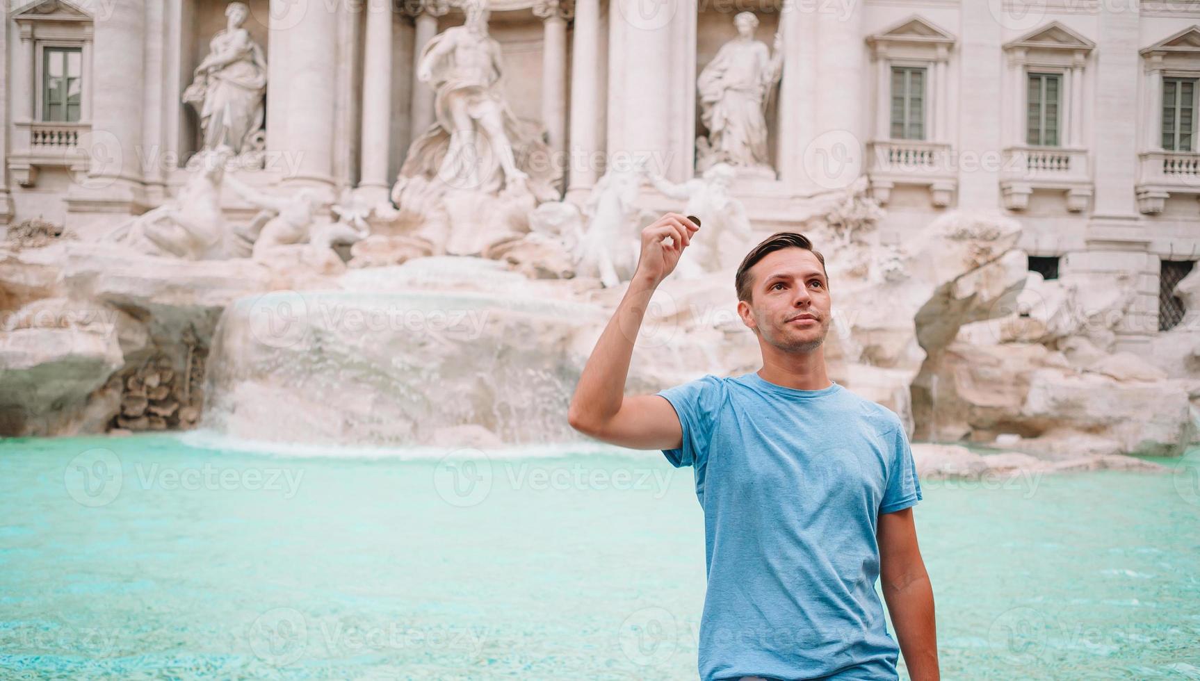 Young man near fountain Fontana di Trevi with coins in hands photo