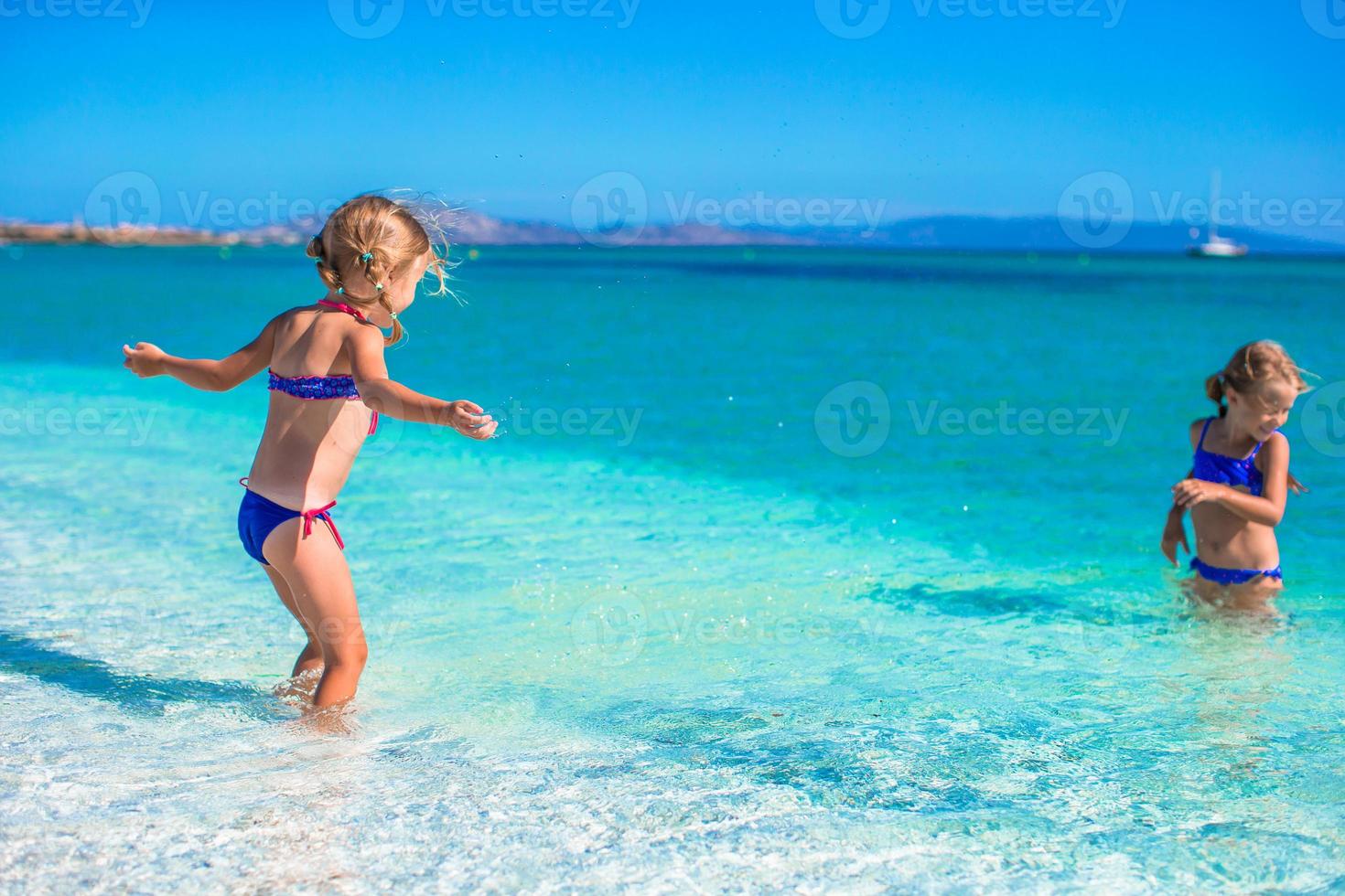 adorables niñas se divierten en aguas poco profundas en la playa tropical foto