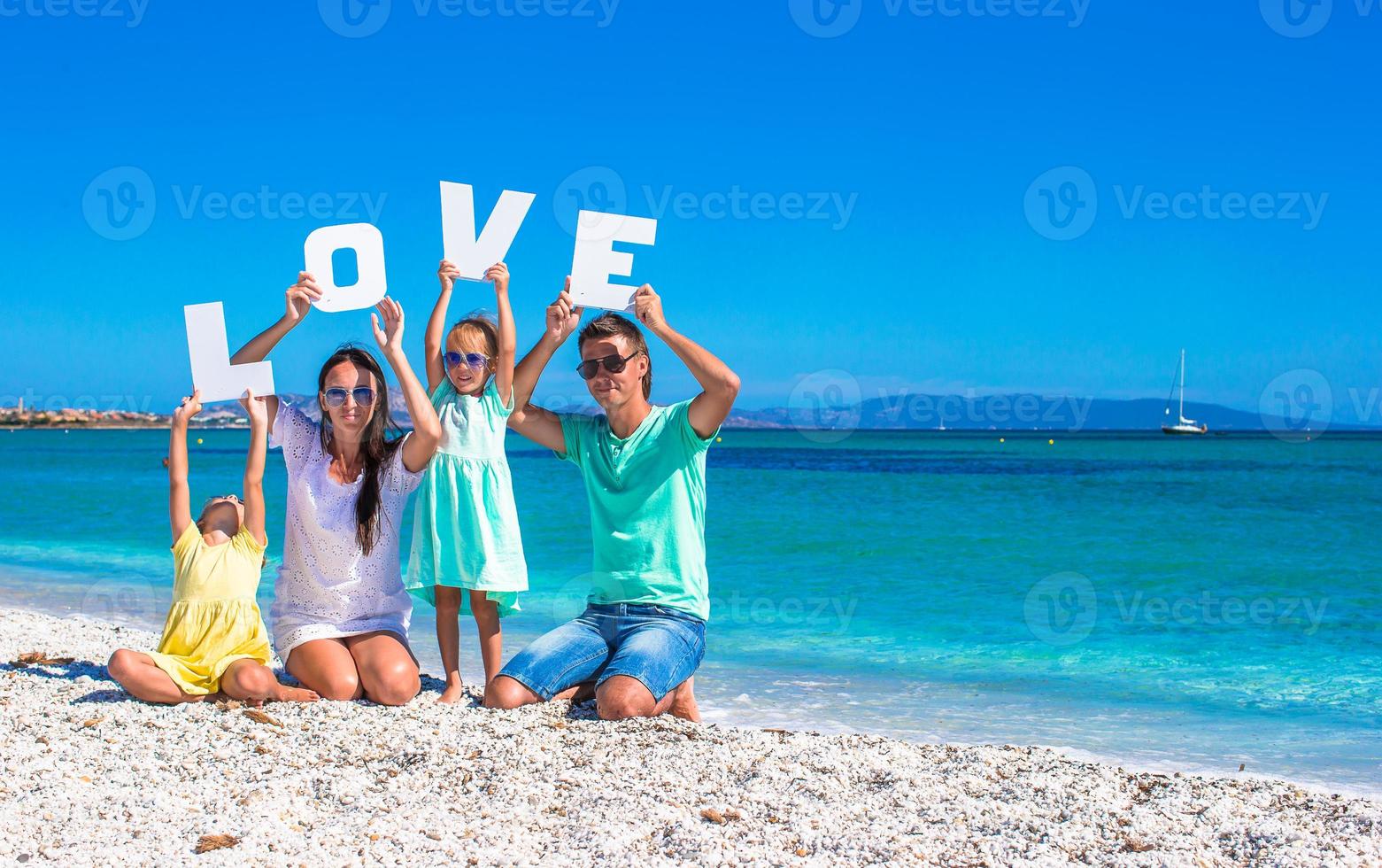 Young beautiful family of four with word love on beach photo