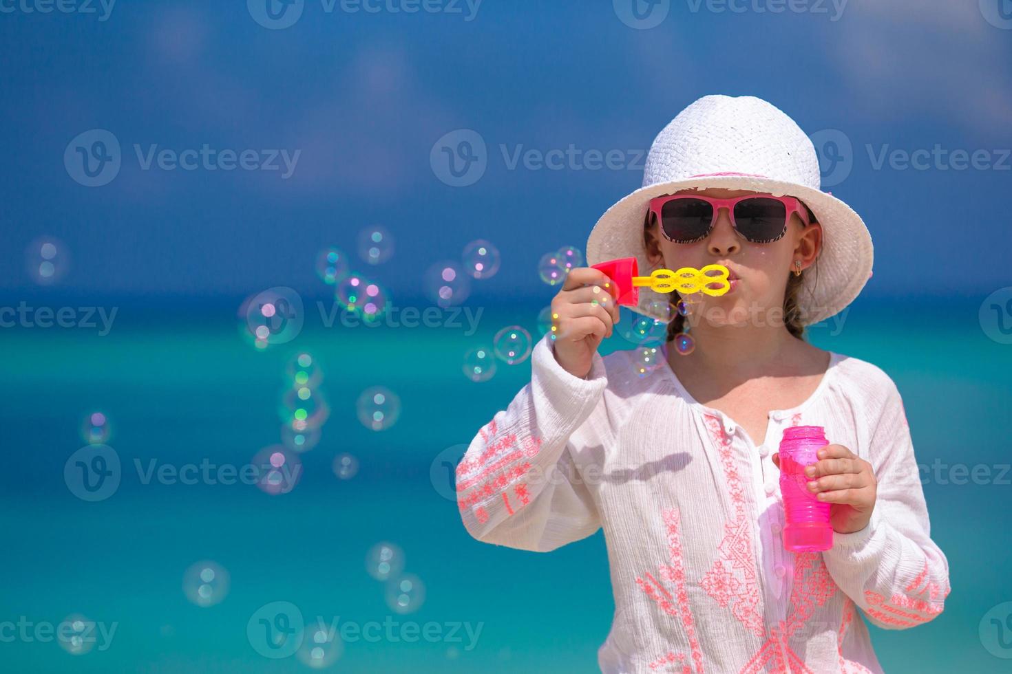 Adorable little girl making soap bubbles during summer vacation photo