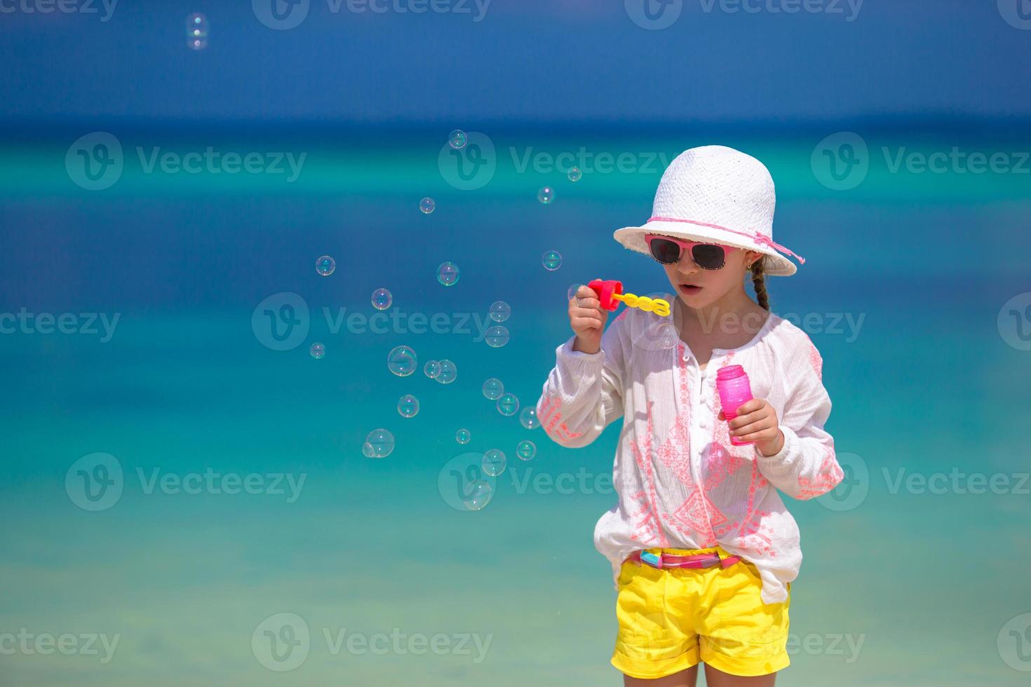 Adorable little girl making soap bubbles during summer vacation photo