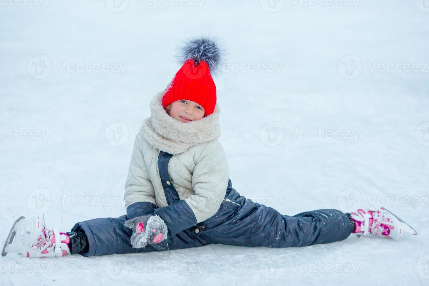 Little adorable girl sitting on ice with skates after fall photo