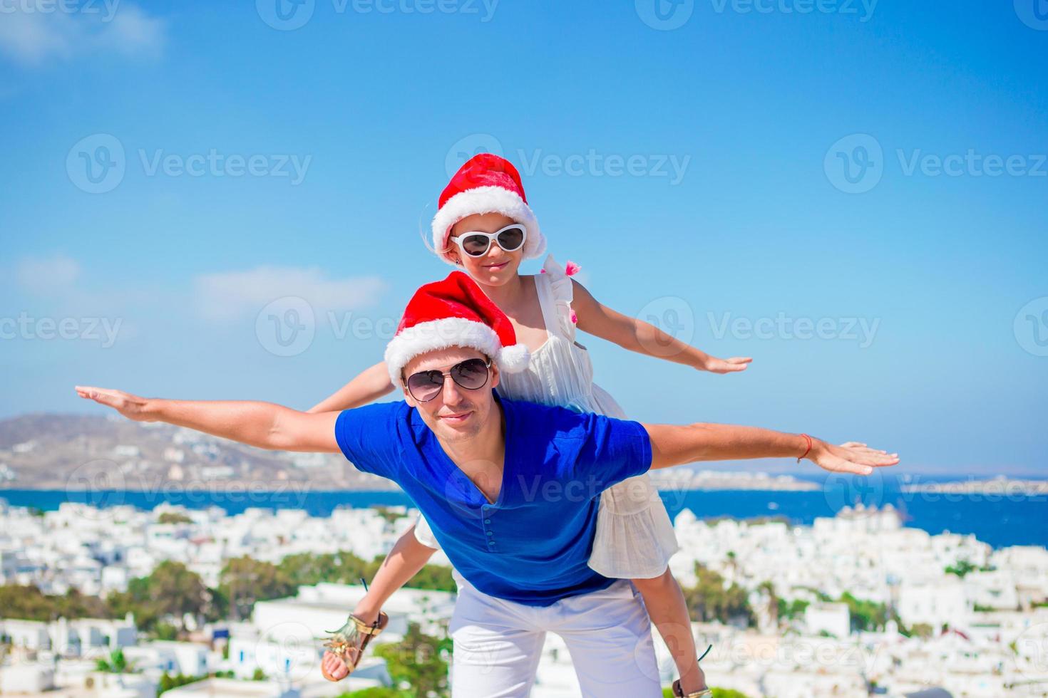 familia en sombreros de santa disfruta de vacaciones griegas con hermosa vista foto