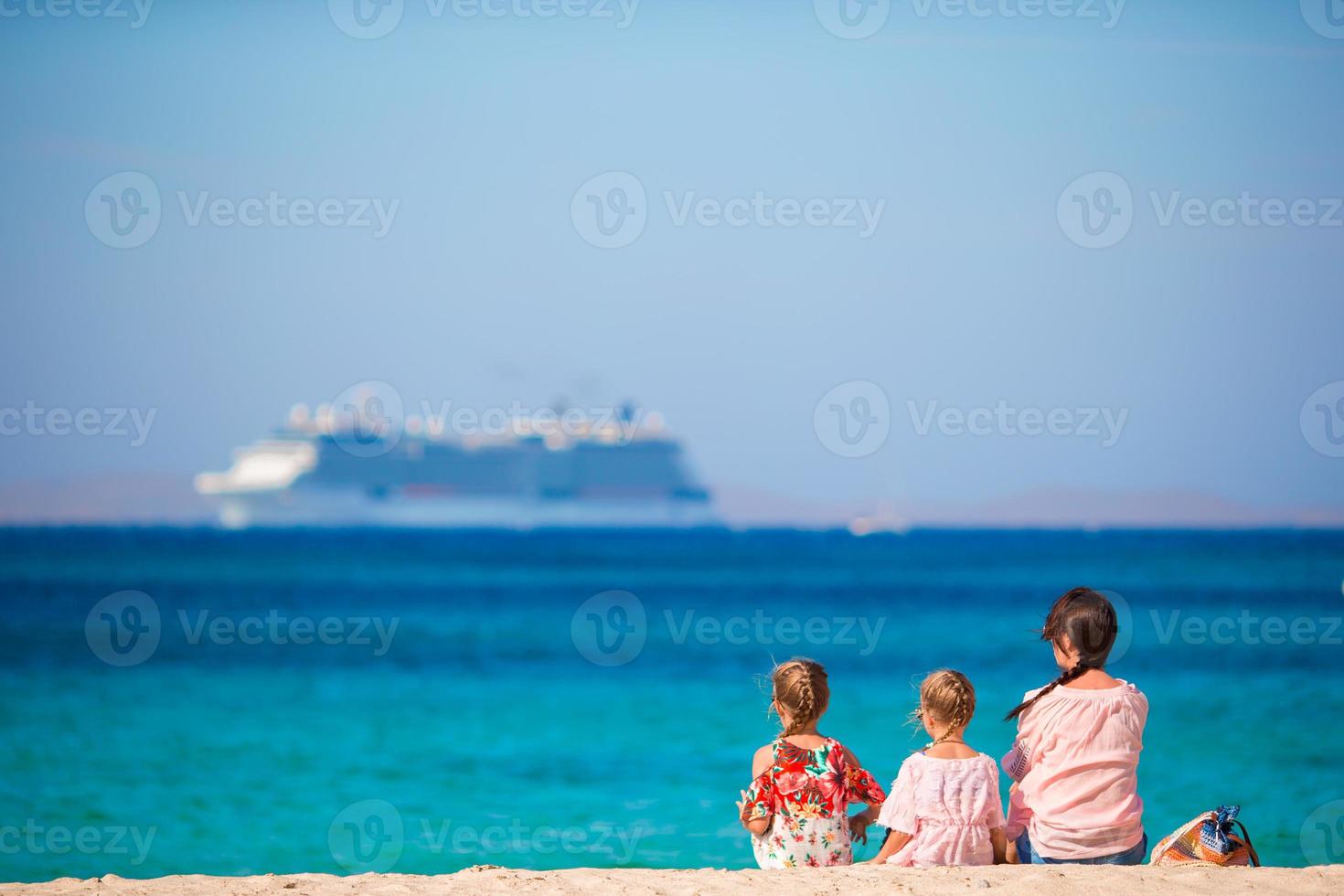 la familia en la playa se relaja y mira el horizonte. mamá e hijos disfrutan de vacaciones europeas foto