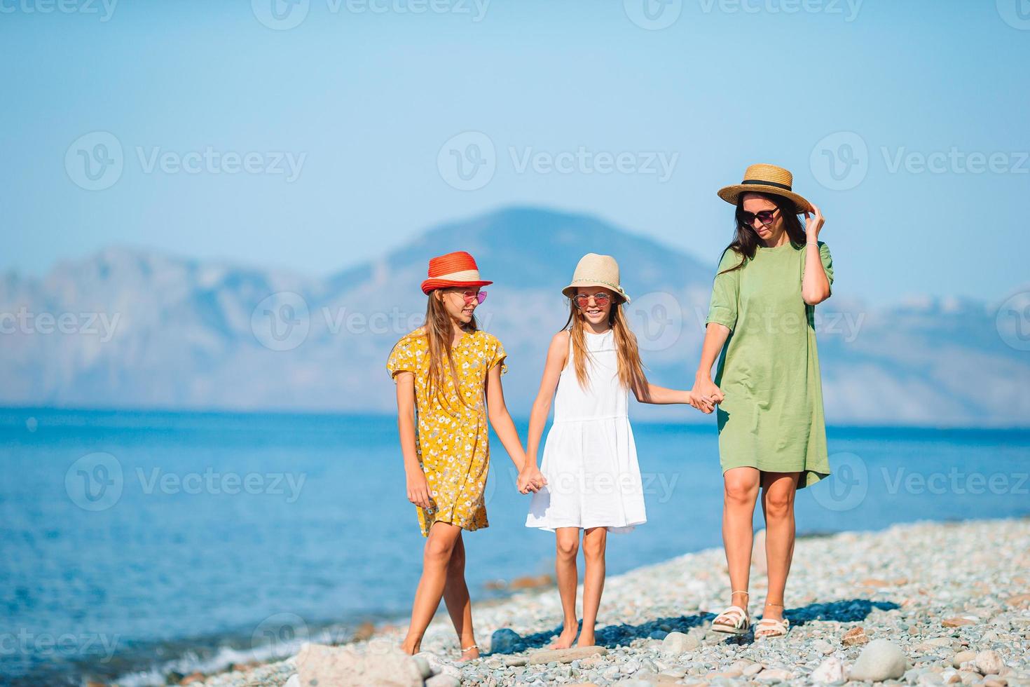 Adorable little girls and young mother on tropical white beach photo