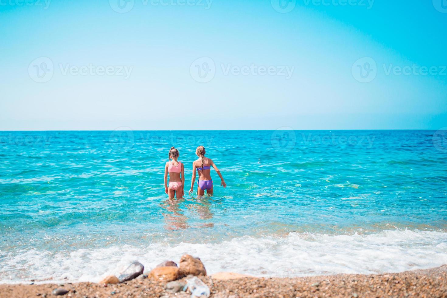 Little happy funny girls have a lot of fun at tropical beach playing together. photo