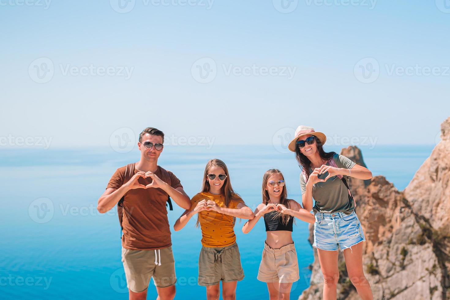 Happy family of four walking in the mountains on the sunset photo