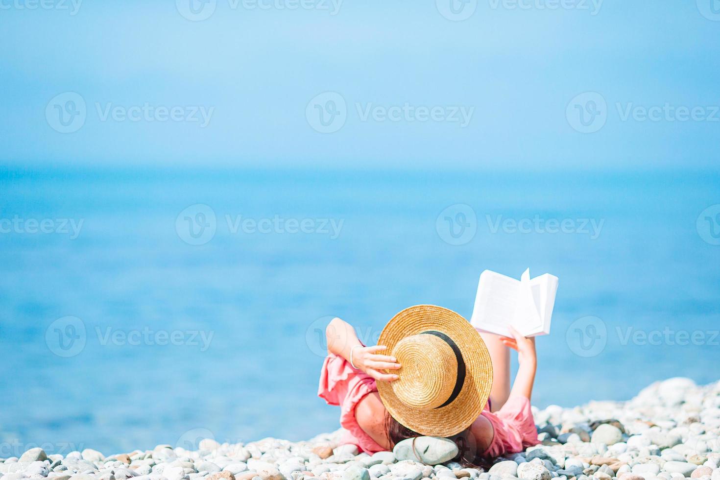 Young woman reading book during tropical white beach photo