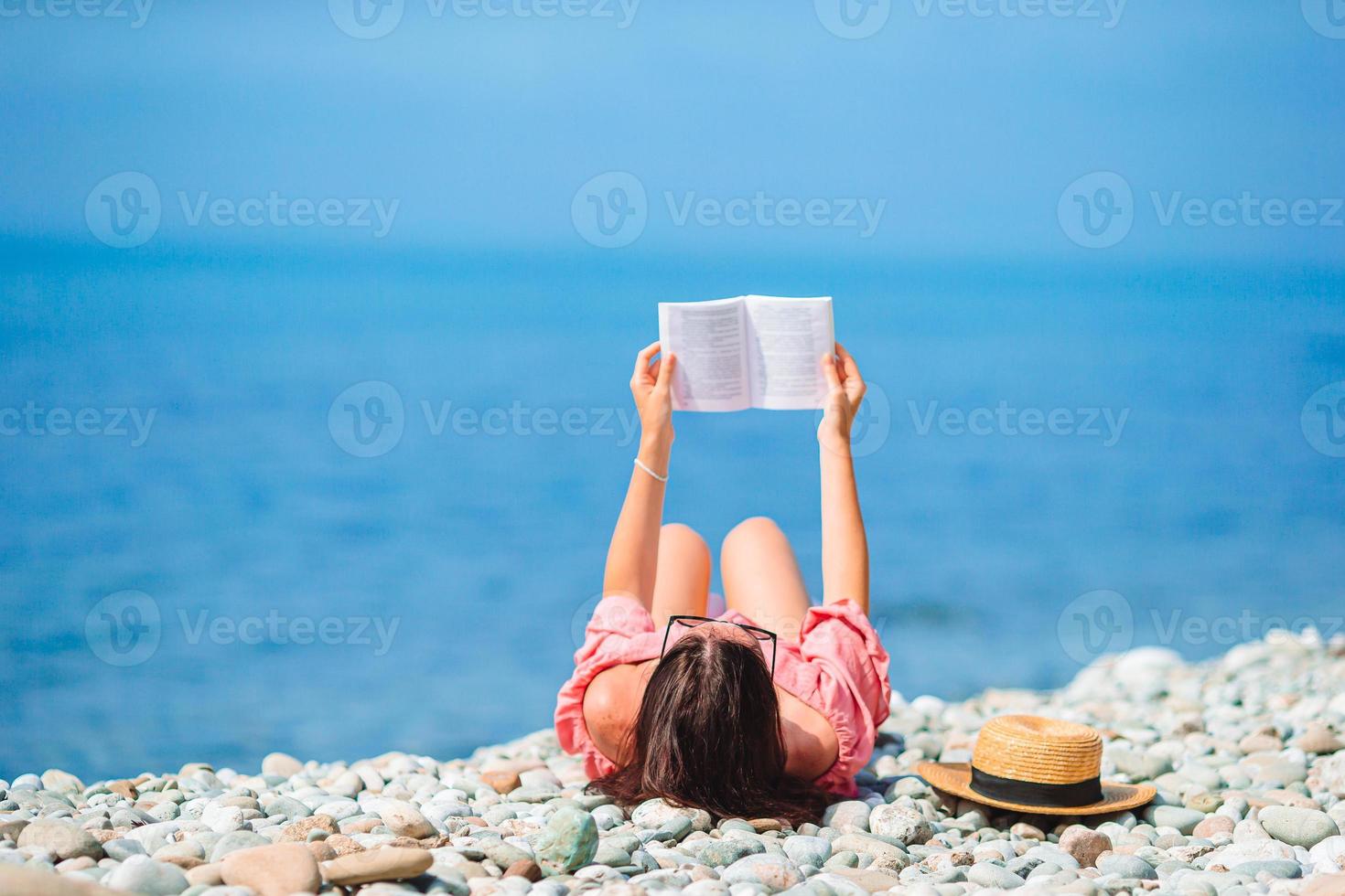Young woman reading book during tropical white beach photo