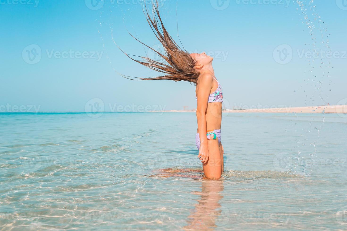 Adorable active little girl at beach during summer vacation photo