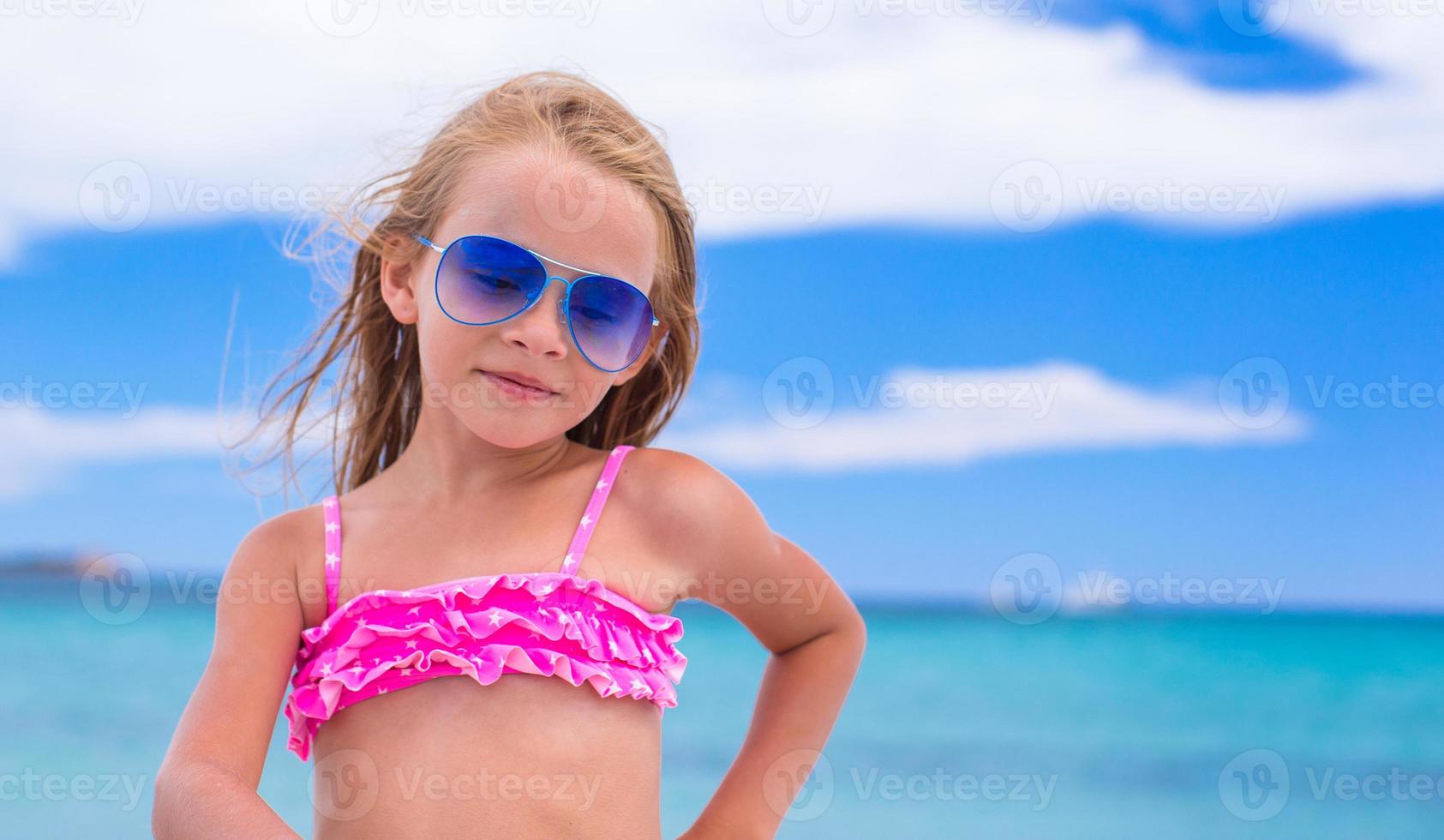 Portrait of little girl at tropical beach during vacation photo