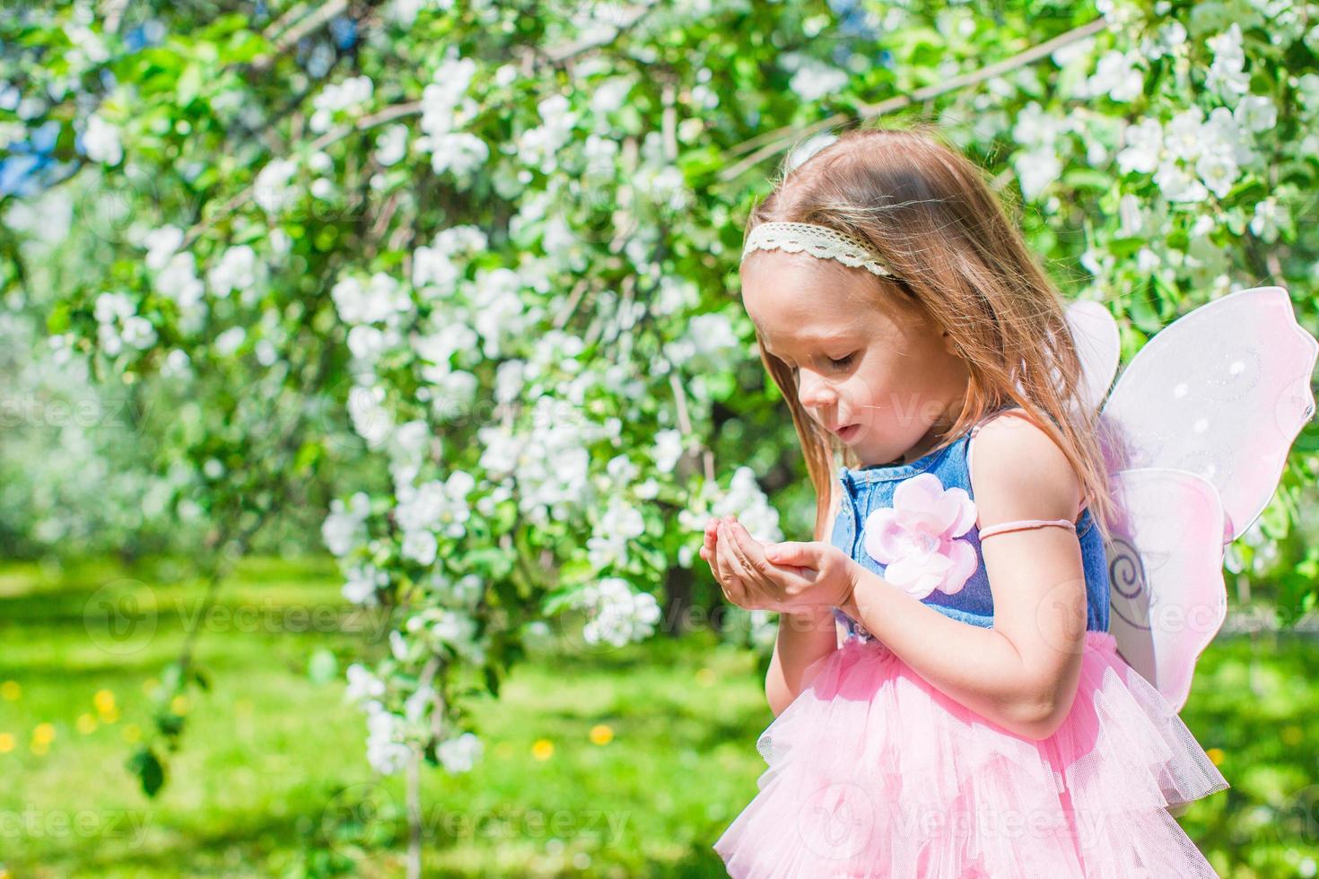 Adorable little girl in blossoming apple tree garden photo