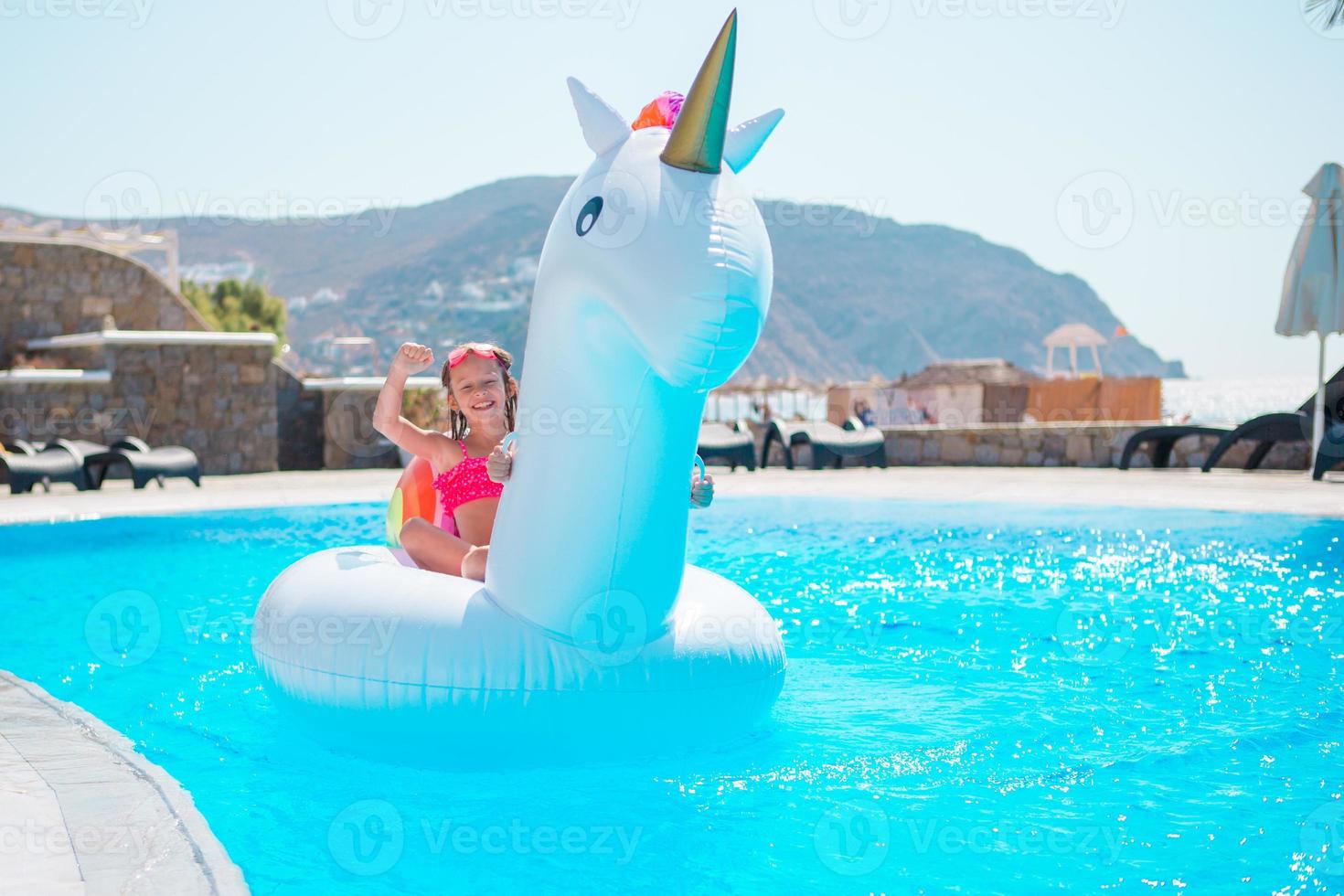 Adorable little girls at outdoor swimming pool having fun together photo